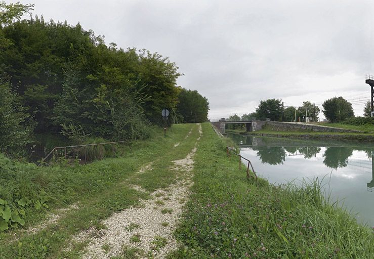 La rigole par rapport au canal : elle arrive à gauche, son passage sous le chemin de halage est signalé par un garde corps de chaque côté. A droite, le canal enjambé par le pont IA89001050. © Thierry Kuntz / Région Bourgogne-Franche-Comté, Inventaire du patrimoine - 2011
