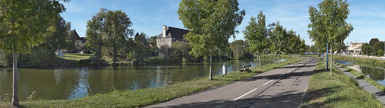 L'ancien château de la Motte-Bouchot : les écuries réaménagées en habitation pour les ouvriers de l'ancienne tuilerie sont installées le long de l'étang de la Motte, parallèlement au canal. Au fond, la mairie. © Thierry Kuntz / Région Bourgogne-Franche-Comté, Inventaire du patrimoine - 2012