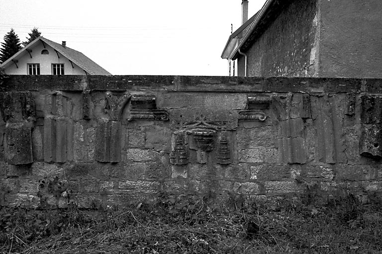 Vestiges de l'ancienne église, insérés dans le mur d'enclos du presbytère. © Gilbert Poinsot / Région Bourgogne-Franche-Comté, Inventaire du patrimoine - 1975