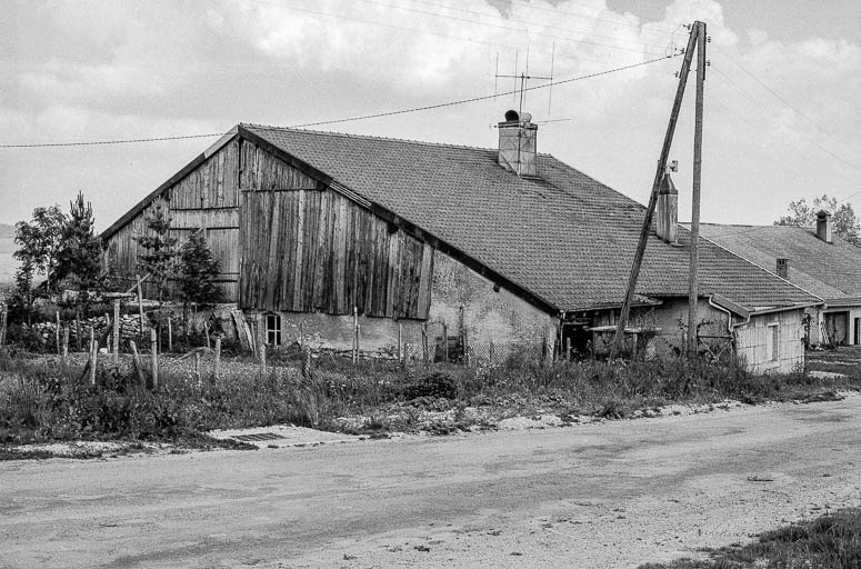 Ferme située 32 rue de Salins : façades latérale et postérieure avec débord de la partie habitation, pignon fermé par des planches et montée de grange. © Gilbert Poinsot / Région Bourgogne-Franche-Comté, Inventaire du patrimoine - 1975