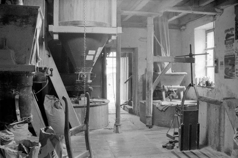 Intérieur : rez-de-chaussée, salle des meules. Trémie à farine à gauche et potence à droite, en avant des deux paires de meules. © Laurent Poupard / Région Bourgogne-Franche-Comté, Inventaire du patrimoine - 1988