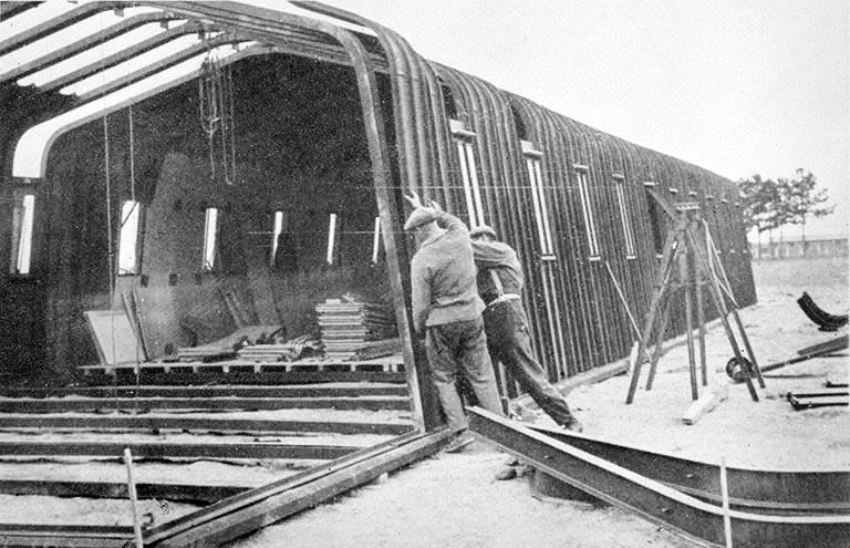 Montage d'un baraquement métallique dans les années 1940 : mise en place d'une tôle du mur. © Jérôme  Mongreville (reproduction) / Région Bourgogne-Franche-Comté, Inventaire du patrimoine - 1993