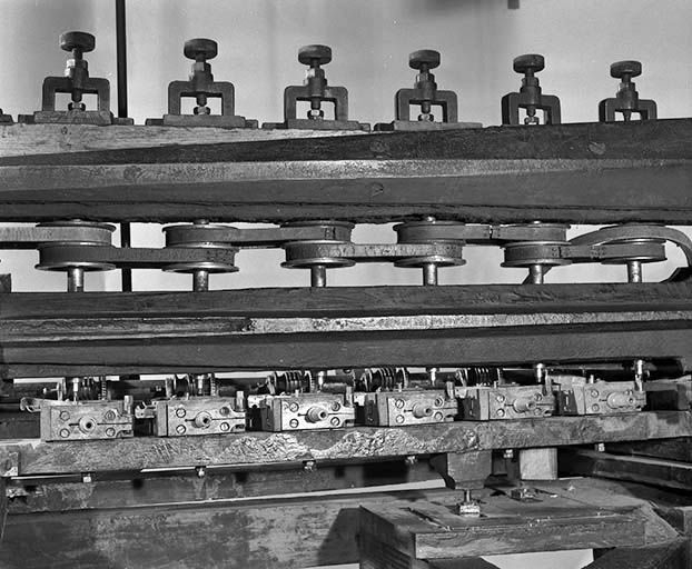 Face arrière : système moteur des fraises et supports des ébauchons. Le mouvement est transmis aux fraises à l'aide des poulies et des courroies en partie supérieure. Les ébauchons sont emboîtés dans les mandrins coniques en partie basse. © Jérôme Mongreville / Région Bourgogne-Franche-Comté, Inventaire du patrimoine - 2000