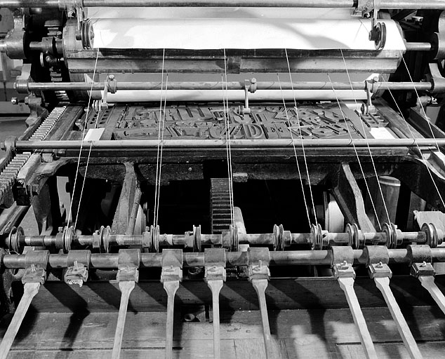 Partie arrière de la machine, vue de face. Les fils permettent de soutenir la feuille qui sera déposée sur la table de réception, à droite, à l'aide du receveur mécanique à raquettes. © Jérôme Mongreville / Région Bourgogne-Franche-Comté, Inventaire du patrimoine - 2001