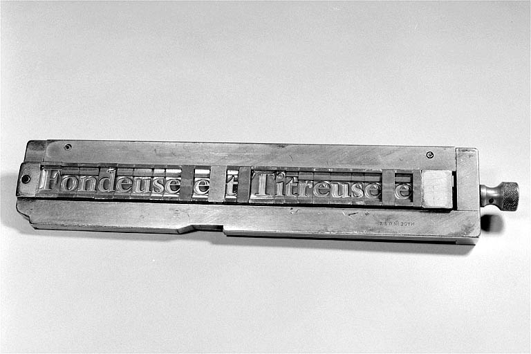 Face inférieure d'un composteur, matrices de caractères en place. Le caractère apparaît en négatif dans chaque matrice. © Jérôme Mongreville / Région Bourgogne-Franche-Comté, Inventaire du patrimoine - 2002