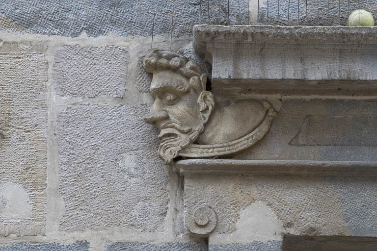 Logis principal, façade sur rue, partie droite, rez-de-chaussée, baie à droite de l'arcade boutiquière : mascaron gauche. © Yves Sancey / Région Bourgogne-Franche-Comté, Inventaire du patrimoine - 2011