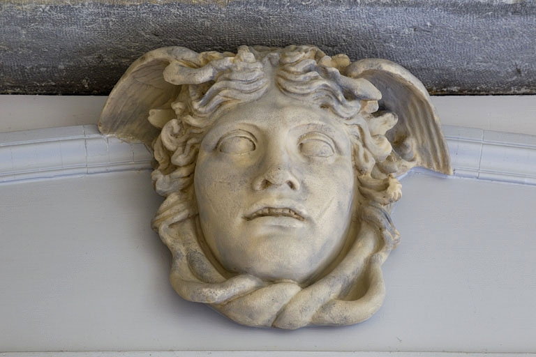 Escalier à cage ouverte, détail du décor d'un dessus de porte : sculpture représentant une tête ailée. © Yves Sancey / Région Bourgogne-Franche-Comté, Inventaire du patrimoine - 2011