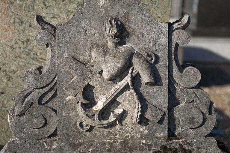 Tombeau précédent. Détail : panneau au pied de la croix représentant un relief composé d'une croix, d'une ancre et d'un coeur enflammé. © Mary Ruffinoni / Région Bourgogne-Franche-Comté, Inventaire du patrimoine - 2012
