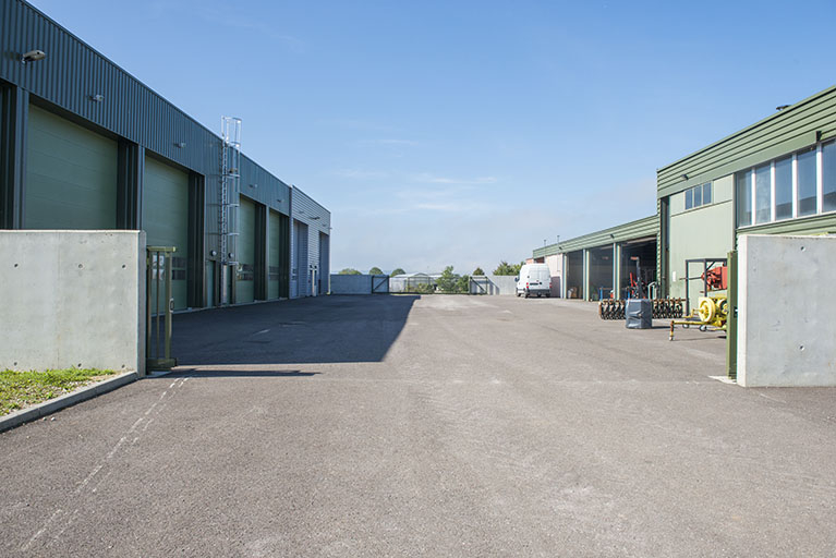 Cour et façade nord des halles de machinisme au sud et et façade sud de la halle d'agroéquipement au nord.  © Mary Ruffinoni / Région Bourgogne-Franche-Comté, Inventaire du patrimoine - 2013