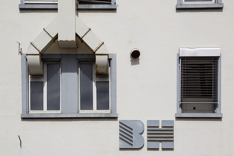 Usine, 1er corps de bâtiment : fenêtre horlogère et logotype, sur la façade latérale gauche. © Sonia Dourlot / Région Bourgogne-Franche-Comté, Inventaire du patrimoine - 2014 Usine, 1er corps de bâtiment : fenêtre horlogère et logotype, sur la façade latérale gauche. © Sonia Dourlot / Région Bourgogne-Franche-Comté, Inventaire du patrimoine - 2014