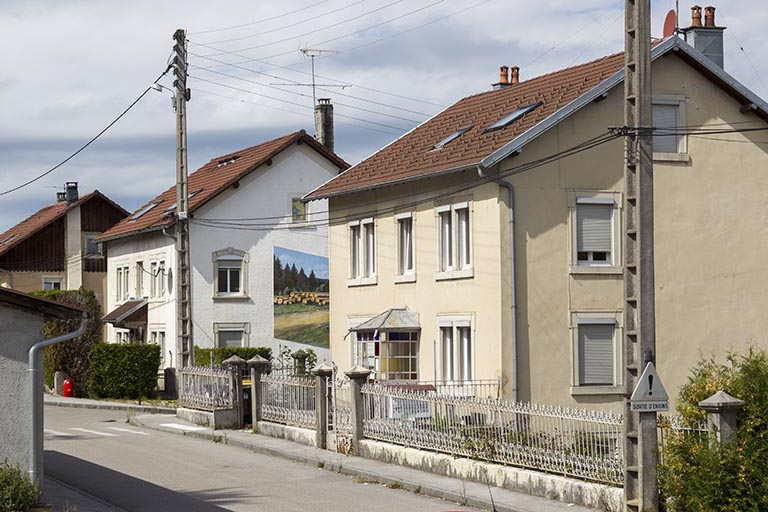 Extrémité ouest de la Rue Neuve (vers la rue de la Scierie). Du premier plan à l'arrière-plan : atelier d'horlogerie Domon Frères (n° 14), logement de la scierie Taillard (n° 16) et atelier de traitement thermique des métaux, de polissage et de galv… © Sonia Dourlot / Région Bourgogne-Franche-Comté, Inventaire du patrimoine - 2014 Extrémité ouest de la Rue Neuve (vers la rue de la Scierie). Du premier plan à l'arrière-plan : atelier d'horlogerie Domon Frères (n° 14), logement de la scierie Taillard (n° 16) et atelier de traitement thermique des métaux, de polissage et de galv… © Sonia Dourlot / Région Bourgogne-Franche-Comté, Inventaire du patrimoine - 2014