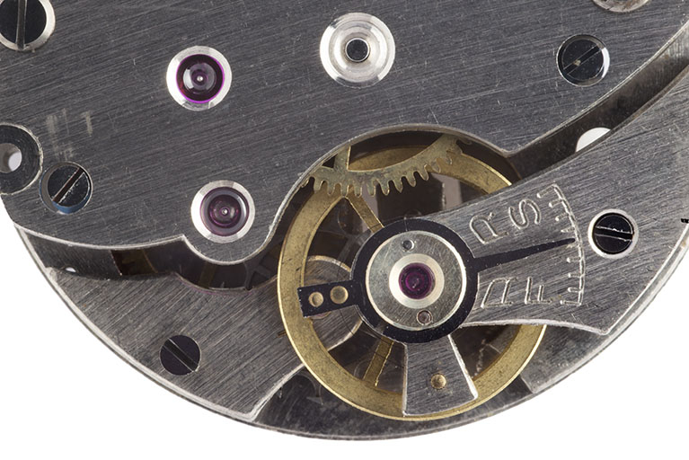 1er mouvement, détail côté ponts : balancier-spiral et mécanisme de réglage de la marche diurne. La roue de cylindre se devine à l'arrière-plan. © Sonia Dourlot / Région Bourgogne-Franche-Comté, Inventaire du patrimoine - 2015