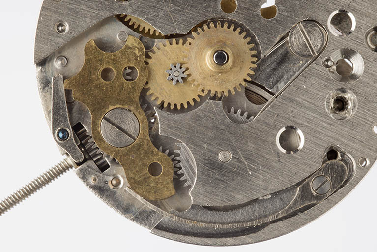 2e mouvement, côté cadran : mécanisme du remontoir. De gauche à droite, tige de remontoir et son pignon, plaque protégeant les renvois, roue de minuterie et son pignon, canon. © Sonia Dourlot / Région Bourgogne-Franche-Comté, Inventaire du patrimoine - 2015