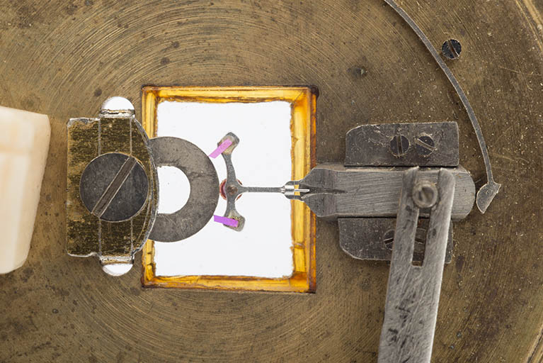 Vue de détail de l'outil. De gauche à droite : la rondelle et sa fixation, l'ancre (dont les deux palettes sont en appui contre la rondelle), la coulisse et son ressort. © Sonia Dourlot / Région Bourgogne-Franche-Comté, Inventaire du patrimoine - 2015