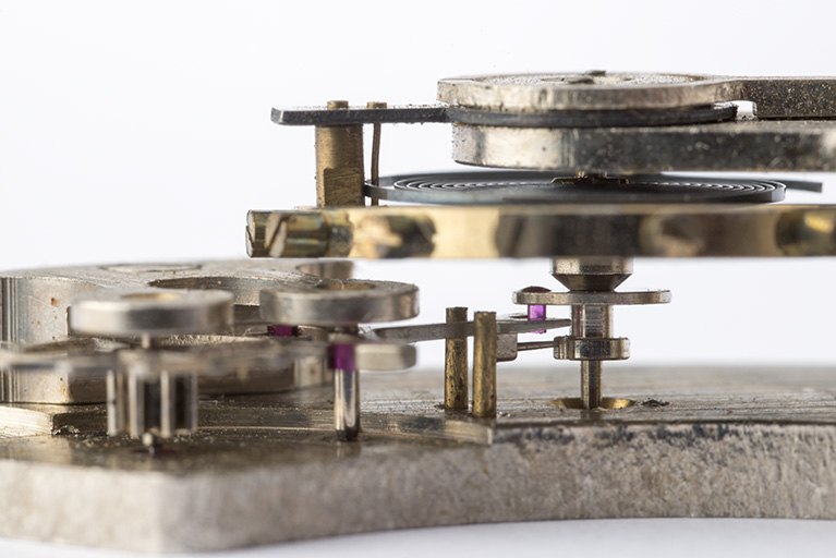 L'échappement : plateau du balancier muni de l'ellipse (cheville en rubis) engagée dans la fourchette de l'ancre. Le mouvement de cette dernière, dont le dard est visible au-dessous, est limité par les deux goupilles en laiton. © Sonia Dourlot / Région Bourgogne-Franche-Comté, Inventaire du patrimoine - 2015