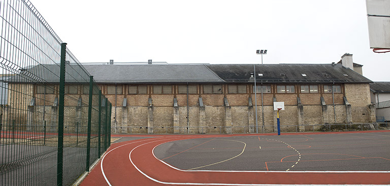 Terrain de sport et façade nord-est de l'ancien manège-atelier. © Mary Ruffinoni / Région Bourgogne-Franche-Comté, Inventaire du patrimoine - 2015