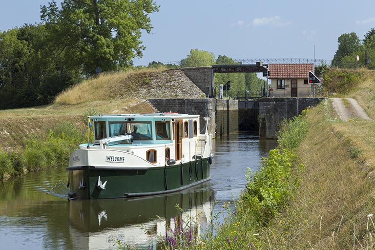 Bateau de plaisance et l'écluse en arrière-plan. © Sonia Dourlot / Région Bourgogne-Franche-Comté, Inventaire du patrimoine - 2015 Bateau de plaisance et l'écluse en arrière-plan. © Sonia Dourlot / Région Bourgogne-Franche-Comté, Inventaire du patrimoine - 2015