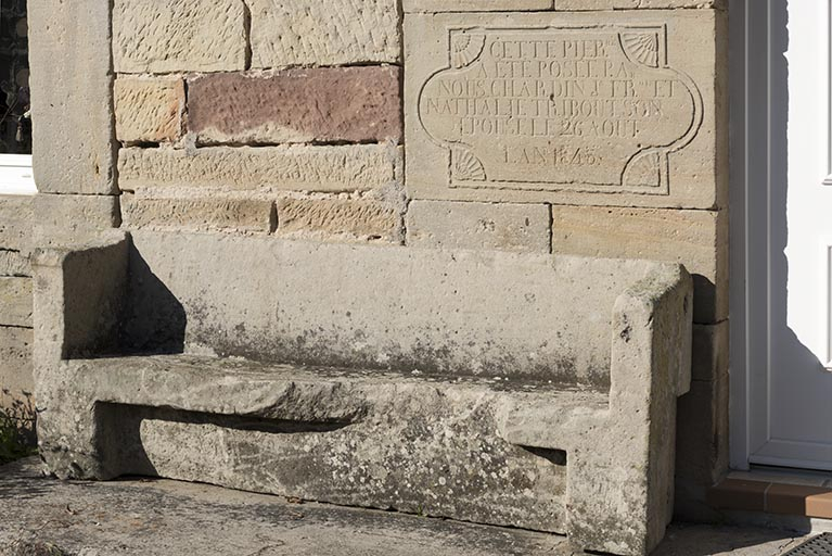 Détail de l'inscription de fondation (1845) et du banc devant la façade antérieure de la maison, 14 rue Principale.  © Sonia Dourlot / Région Bourgogne-Franche-Comté, Inventaire du patrimoine - 2015