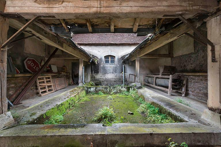 Le bassin du lavoir entouré de sa galerie couverte, dans le prolongement de la remise de pompe à incendie. © Jérôme Mongreville / Région Bourgogne-Franche-Comté, Inventaire du patrimoine - 2016