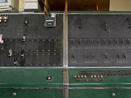 Détail du poste électrique néoclassique à leviers d'itinéraires : en haut à droite, commutateurs de fermeture d'urgence, en bas à droite boutons d'annonces et d'annulation d'annonces avec Perrigny poste-1. © Région Bourgogne-Franche-Comté, Inventaire du patrimoine