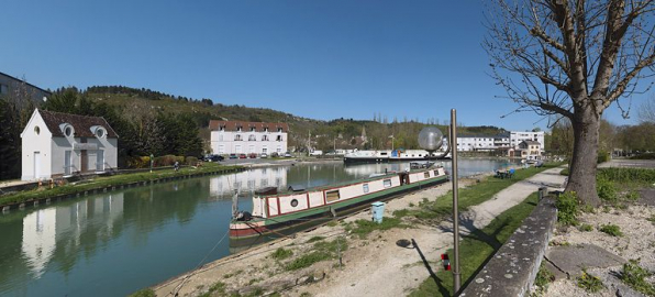 Le port, vu d'amont, petite construction moderne à gauche, puis gare ferroviaire transformée en immeuble à logements. Site d'écluse au fond. Au premier plan, un bateau anglais. © Région Bourgogne-Franche-Comté, Inventaire du patrimoine