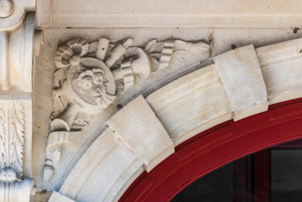 Façade antérieure : instruments de musique sculptés sur l'écoinçon gauche de l'entrée. © Région Bourgogne-Franche-Comté, Inventaire du patrimoine