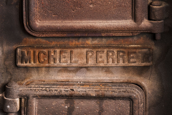Calorifère au sous-sol, détail : plaque de firme ("Michel Perret"). © Région Bourgogne-Franche-Comté, Inventaire du patrimoine Calorifère au sous-sol, détail : plaque de firme ("Michel Perret"). © Région Bourgogne-Franche-Comté, Inventaire du patrimoine