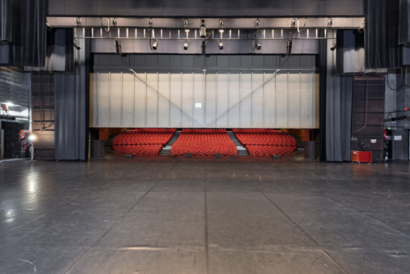 Maison de la culture, grande salle : la salle depuis le fond de la scène, rideau de fer partiellement descendu. © Région Bourgogne-Franche-Comté, Inventaire du patrimoine Maison de la culture, grande salle : la salle depuis le fond de la scène, rideau de fer partiellement descendu. © Région Bourgogne-Franche-Comté, Inventaire du patrimoine