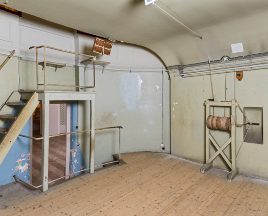 Sous-sol : salle du jeu d'orgue. Estrade du chef d'orchestre au-dessus de la porte et treuil de commande du rideau de scène à droite. © Région Bourgogne-Franche-Comté, Inventaire du patrimoine