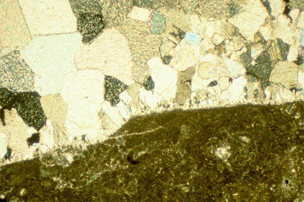 Echantillon de marbre de la Maladière (brèche), vu au microscope. Lame mince montrant un élément de la brèche (sombre) et le ciment de calcite (cristaux jointifs). © Région Bourgogne-Franche-Comté, Inventaire du patrimoine