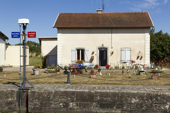 Vue depuis la rive droite de la façade antérieure de la maison d'éclusier et de son jardin d'agrément. © Région Bourgogne-Franche-Comté, Inventaire du patrimoine Vue depuis la rive droite de la façade antérieure de la maison d'éclusier et de son jardin d'agrément. © Région Bourgogne-Franche-Comté, Inventaire du patrimoine