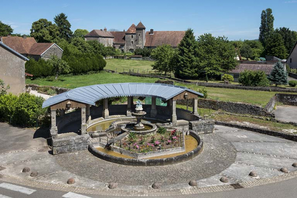 La fontaine sur la place principale du village et la maison fort en arrière plan.  © Région Bourgogne-Franche-Comté, Inventaire du patrimoine