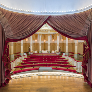 La salle, vue depuis le fond de la scène : rideau de scène, rampes lumineuses, banquettes et sièges de la loge d'honneur. © Région Bourgogne-Franche-Comté, Inventaire du patrimoine