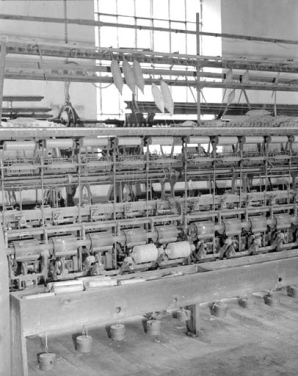 Détail d'une face vue de trois quarts, montrant 7 bobinots.De haut en bas, ratelier de dévidage à 2 niveaux supportant les bobines, tendeur, système de casse-fil, système de croisement des fils sur le bobinot, tambour moteur et bobinot. © Région Bourgogne-Franche-Comté, Inventaire du patrimoine