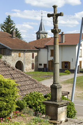 Croix au centre du village avec le clocher de l'église au second plan. © Région Bourgogne-Franche-Comté, Inventaire du patrimoine