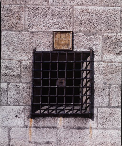 Elévation sur rue : détail, grille d'une fenêtre du cellier dit cave du réfectoire (au centre, fente du "tronc pour les malades de l'hôtel-Dieu"). © Michel Rosso / Région Bourgogne-Franche-Comté, Inventaire du patrimoine - 2004
