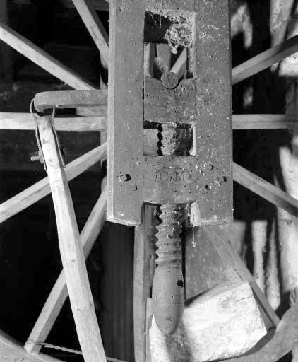 Vis de réglage en hauteur de l'axe de la roue et inscription. À l'arrière-plan, bielle, manivelle et poids équilibrant la roue. © Jérôme Mongreville / Région Bourgogne-Franche-Comté, Inventaire du patrimoine - 1994