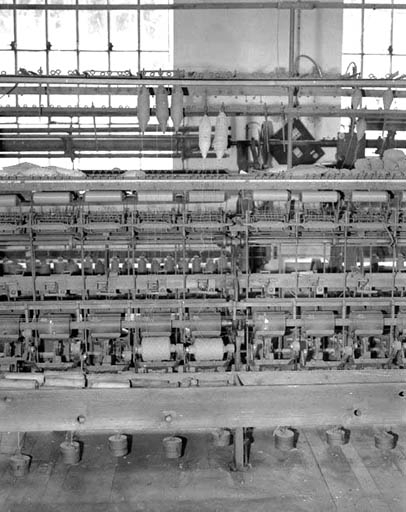 Détail d'une face, montrant 7 bobinots.De haut en bas, ratelier de dévidage à 2 niveaux supportant les bobines, tendeur, système de casse-fil, système de croisement des fils sur le bobinot, tambour moteur et bobinot. © Yves Sancey / Région Bourgogne-Franche-Comté, Inventaire du patrimoine - 1994