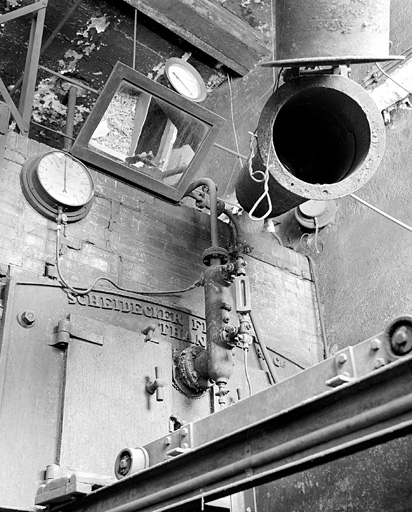 Détail de la partie haute de la chaudière de 1927 (cadrage vertical). Tuyau articulé de chargement de la trémie à droite ; rail et chariot de la trémie en bas. © Yves Sancey / Région Bourgogne-Franche-Comté, Inventaire du patrimoine - 1999