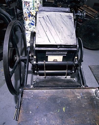 Vue de détail plongeante. Du premier au dernier plan : table de marge, platine et ses raquettes,rouleaux encreurs, marbre équipé d'un dispositif d'emporte-pièce (pour réaliser de la découpe), table d'encrage et soleil. © Jérôme Mongreville / Région Bourgogne-Franche-Comté, Inventaire du patrimoine - 2001