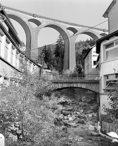 Pont de l'Evalude : vue d'ensemble, depuis la rive droite en aval. En arrière-plan, le grand viaduc de Séjourné portant la voie ferrée Morez - Saint-Claude (tronçon de la ligne Andelot - La Cluse). © Yves Sancey / Région Bourgogne-Franche-Comté, Inventaire du patrimoine - 2003 Pont de l'Evalude : vue d'ensemble, depuis la rive droite en aval. En arrière-plan, le grand viaduc de Séjourné portant la voie ferrée Morez - Saint-Claude (tronçon de la ligne Andelot - La Cluse). © Yves Sancey / Région Bourgogne-Franche-Comté, Inventaire du patrimoine - 2003