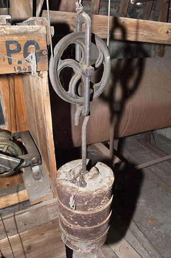 Un des poids actionnant les filins et l'une des inscriptions peintes sur la caisse. © Jérôme Mongreville / Région Bourgogne-Franche-Comté, Inventaire du patrimoine - 2011