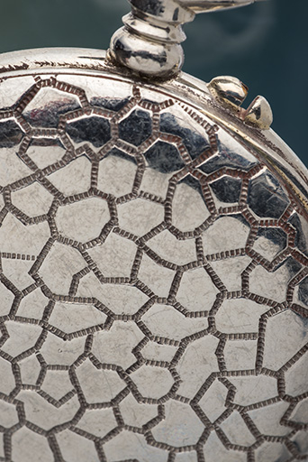 Boîte de montre de gousset en métal chromé : détail du décor imitant le cuir de corcodile. © Sonia Dourlot / Région Bourgogne-Franche-Comté, Inventaire du patrimoine - 2015