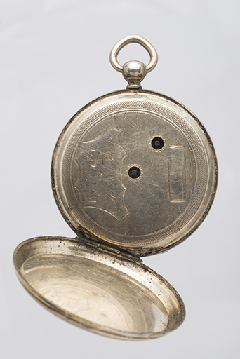 Montre de gousset de la fin du 18e siècle ou du début du 19e siècle : la cuvette. Inscription gravée dans l'écusson : Cylindre / Huit Rubis. Noter les deux trous destinés à la clé utilisée pour le remontage et la mise à l'heure. © Sonia Dourlot / Région Bourgogne-Franche-Comté, Inventaire du patrimoine - 2015