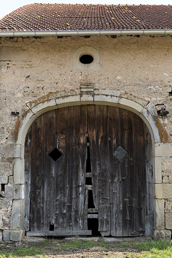 Alignement en bas du village, au nord de la fontaine. Détail de la porte charretière en anse de panier et de l'oculus ovale oblong.  © Sonia Dourlot / Région Bourgogne-Franche-Comté, Inventaire du patrimoine - 2016 Alignement en bas du village, au nord de la fontaine. Détail de la porte charretière en anse de panier et de l'oculus ovale oblong.  © Sonia Dourlot / Région Bourgogne-Franche-Comté, Inventaire du patrimoine - 2016